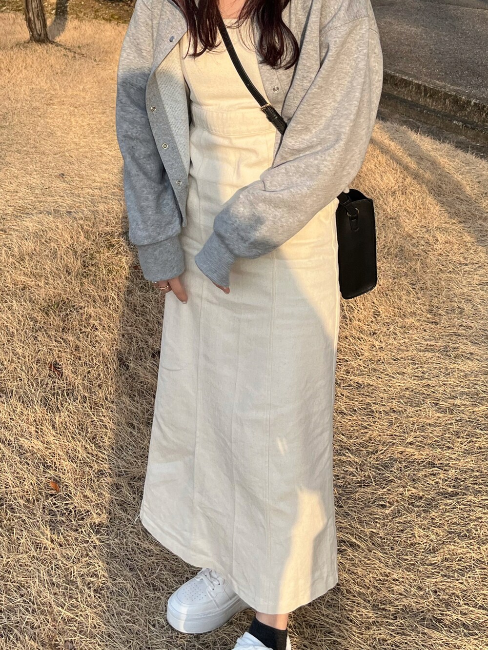 グレー系のカーディガン/ボレロ、ホワイト系のワンピース、ホワイト系のスニーカーを着用したレディースの春コーディネートの2枚目の写真