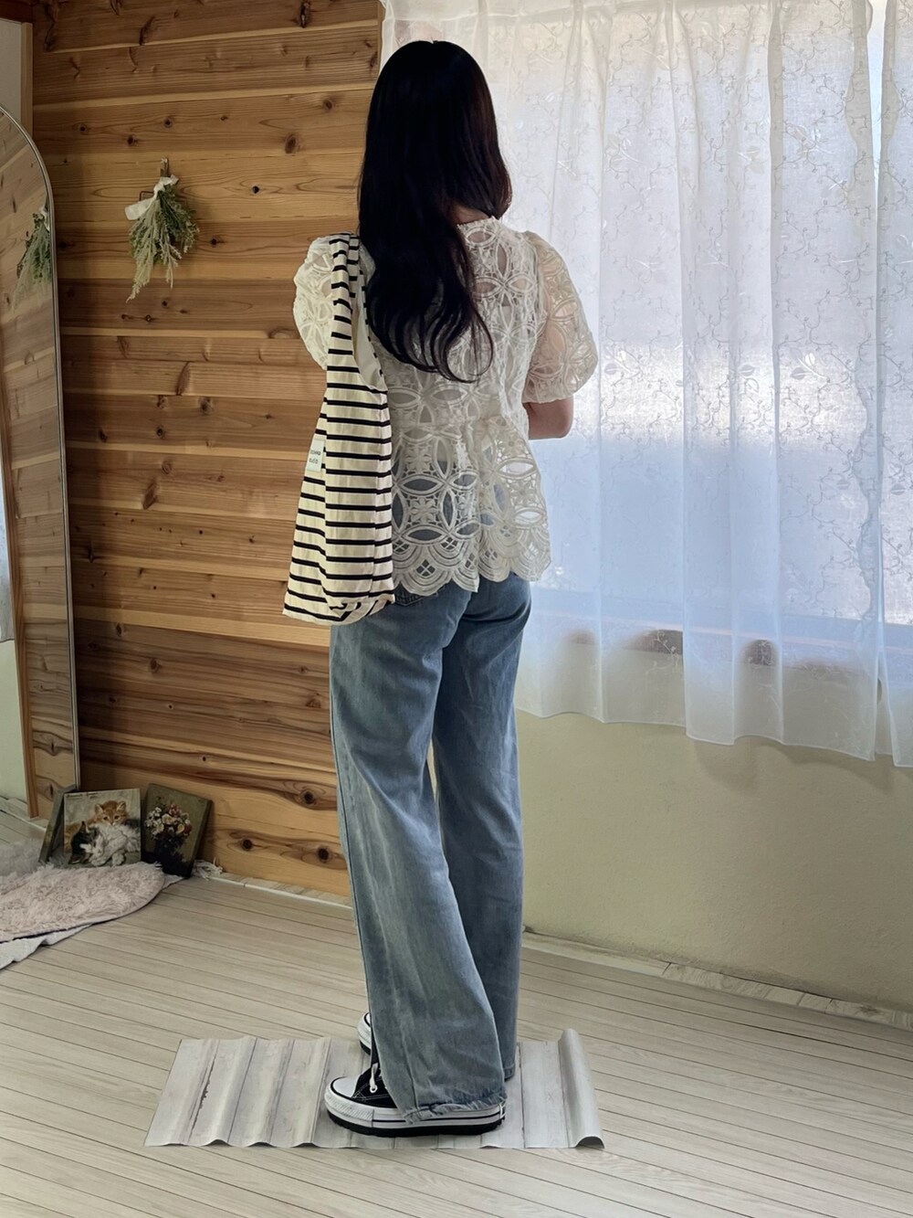 ブルー系のデニムパンツ、ブラック系のスニーカー、ホワイト系のトートバッグを着用したレディースの春コーディネートの2枚目の写真
