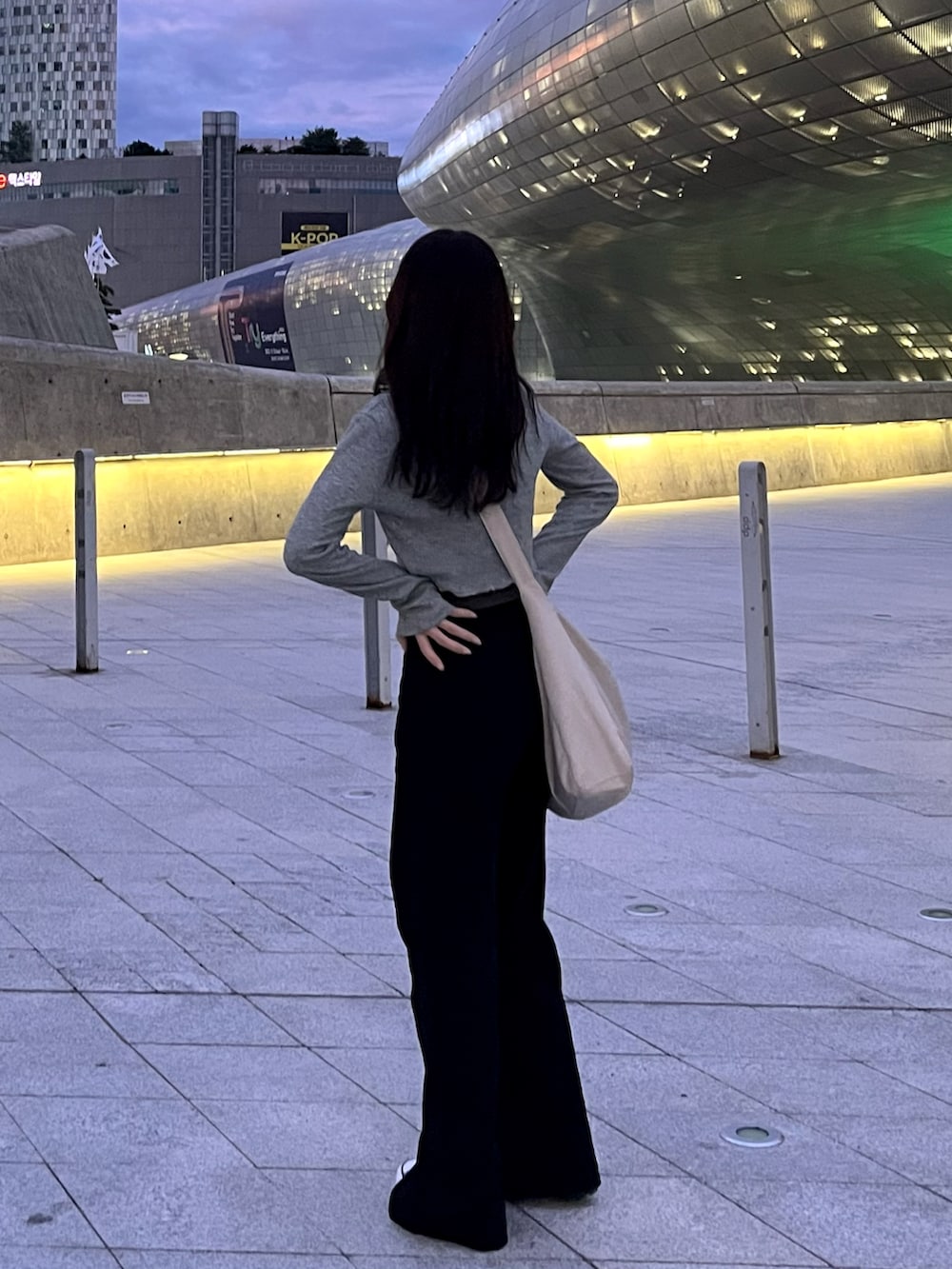 ブラック系のデニムパンツ、ブラック系のスニーカー、グレー系のニット/セーターを着用したレディースの秋コーディネートの2枚目の写真