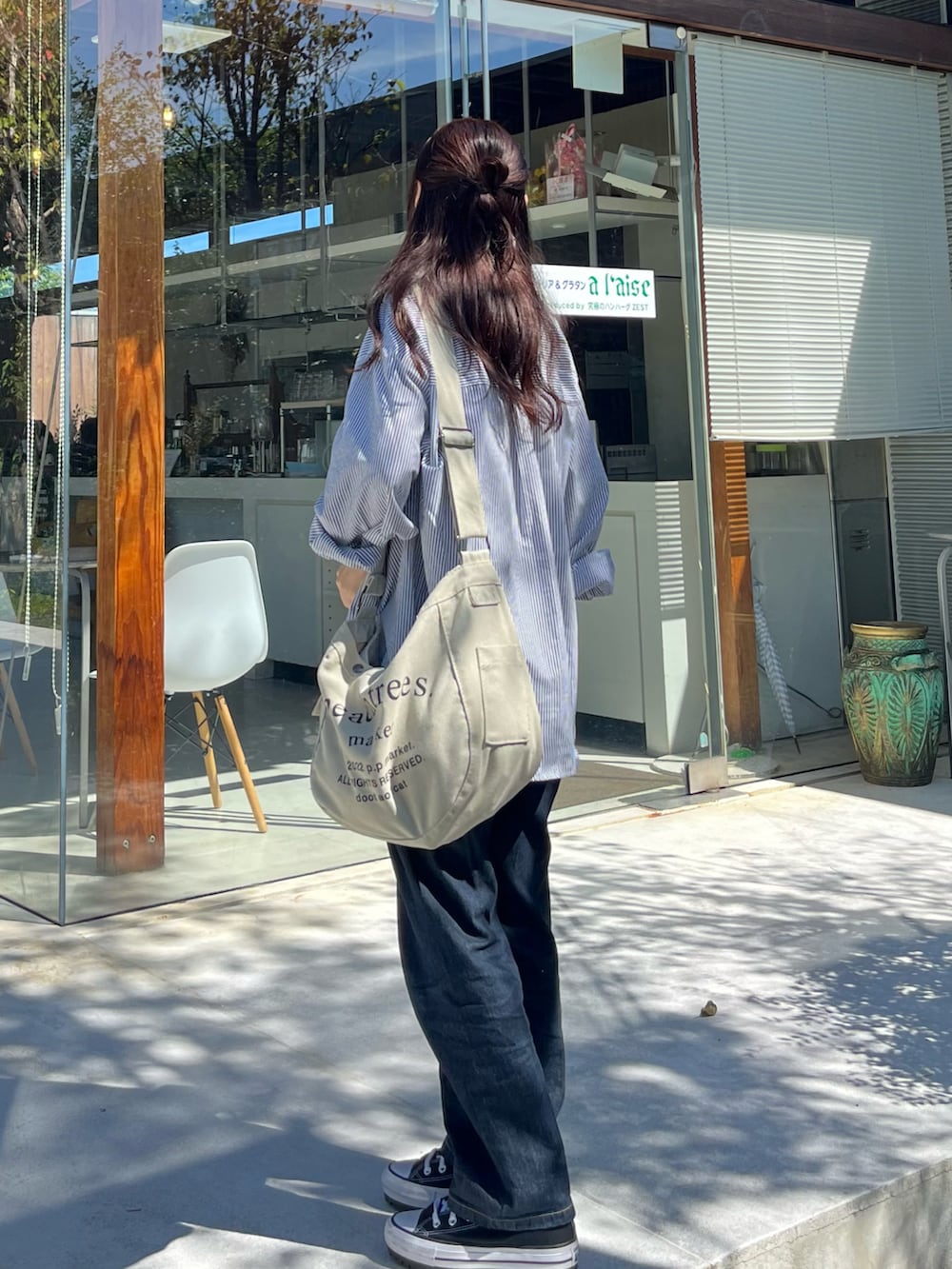 ブラック系のシャツ/ブラウス、ベージュ系のショルダーバッグ、ブルー系のデニムパンツを着用したレディースの秋コーディネートの2枚目の写真