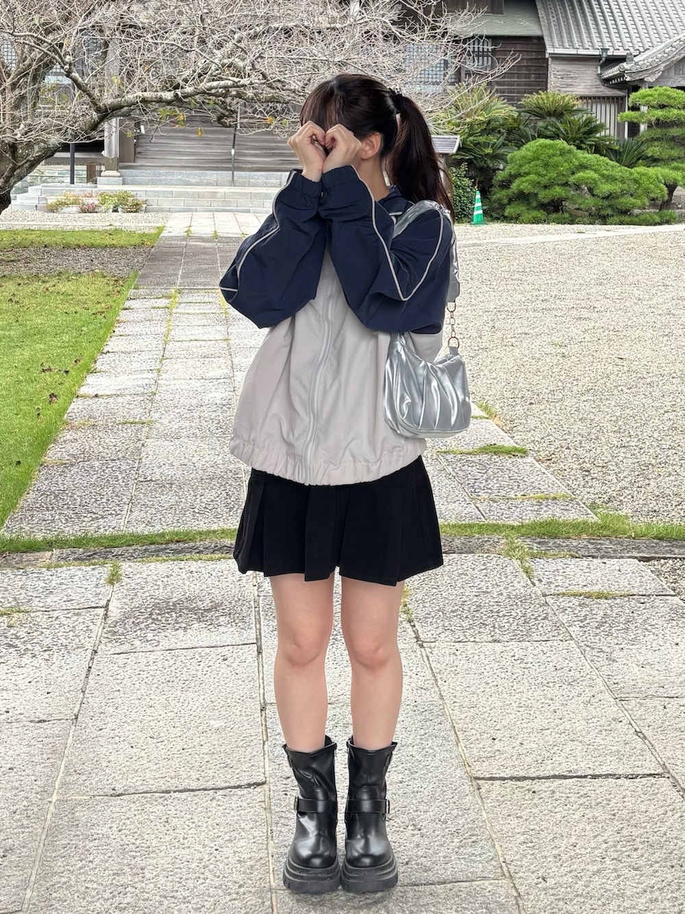 グレー系のナイロンジャケット、シルバー系のハンドバッグ、ブラック系のデニムスカートを着用したレディースの秋コーディネートの2枚目の写真