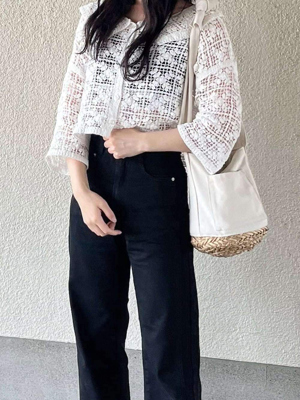 ブラック系のデニムパンツ、ブラック系のスニーカー、ホワイト系のかごバッグを着用したレディースの夏コーディネートの2枚目の写真