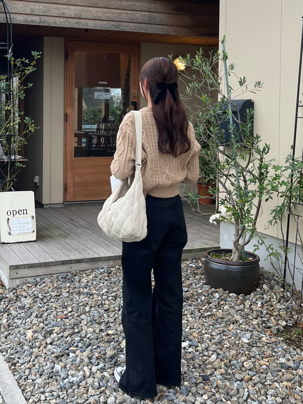ブラック系のデニムパンツ、ブラック系のスニーカー、ホワイト系のショルダーバッグを着用したレディースの冬コーディネートの2枚目の写真
