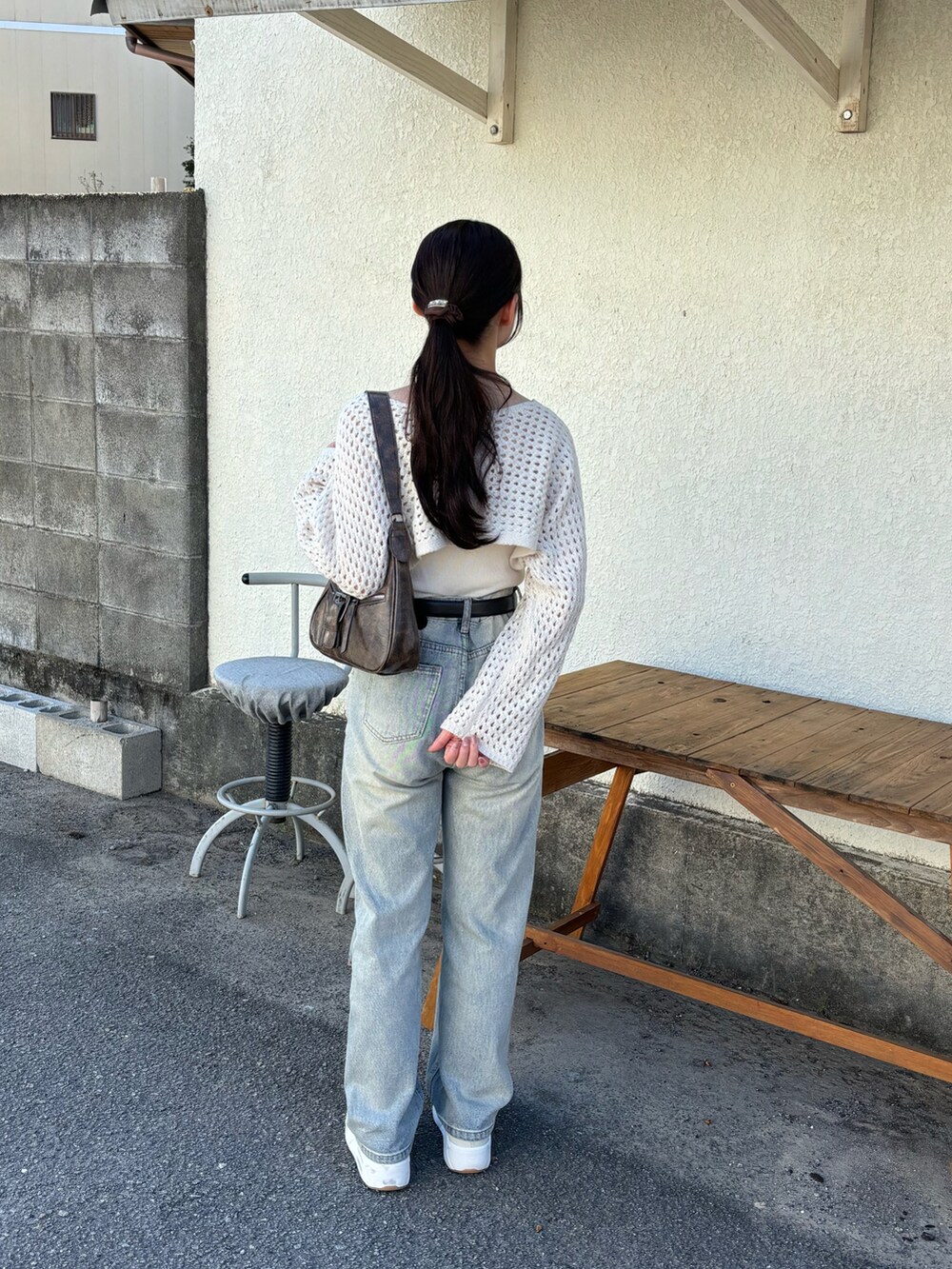 ホワイト系のニット/セーター、ブラウン系のハンドバッグ、ブルー系のデニムパンツを着用したレディースの秋コーディネートの2枚目の写真