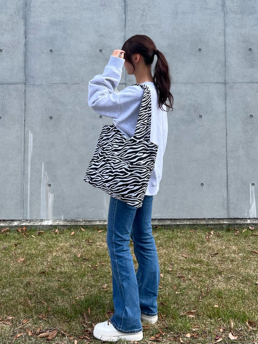 ホワイト系のスウェット、ホワイト系のトートバッグ、ブルー系のデニムパンツを着用したレディースの秋コーディネートの2枚目の写真