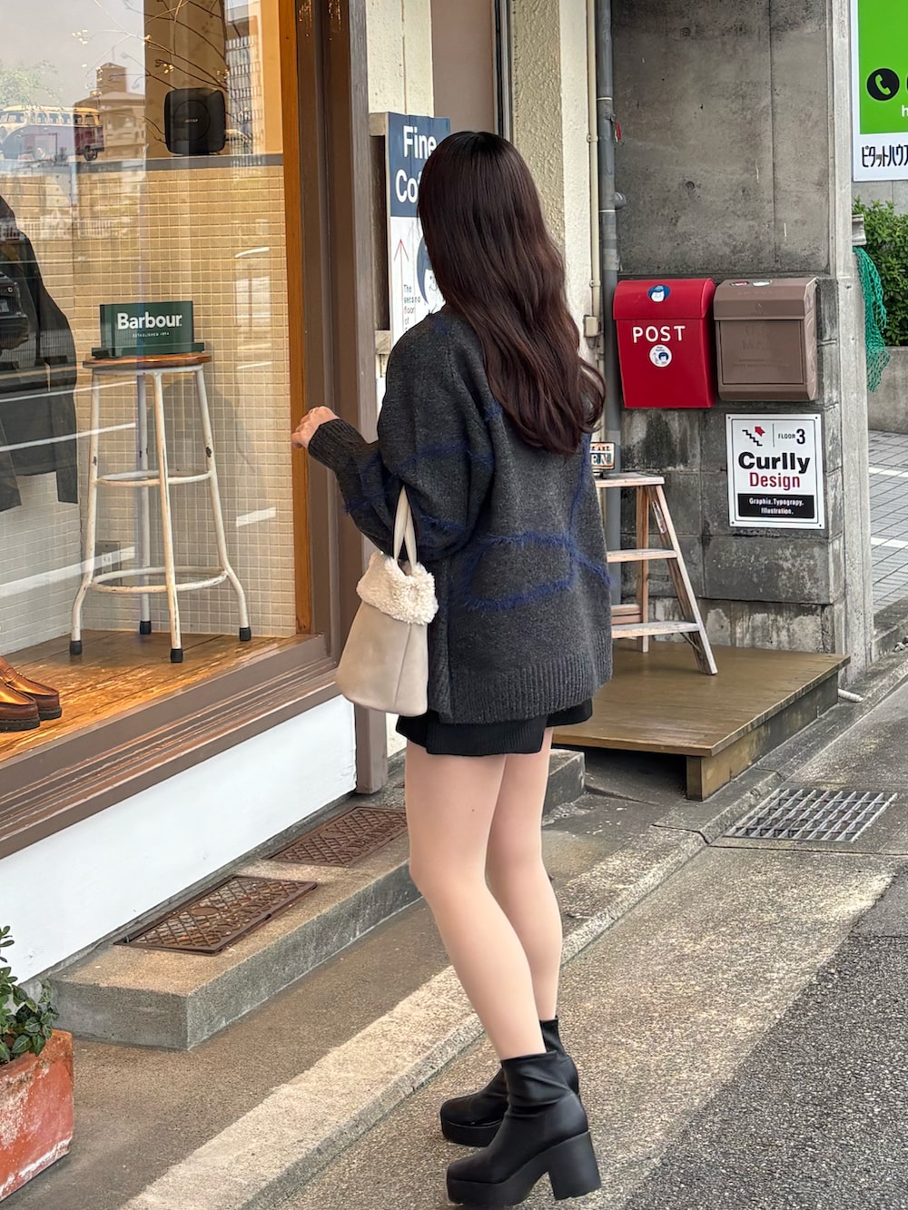 グレー系のニット/セーター、ベージュ系のハンドバッグ、ブラック系のブーツを着用したレディースの冬コーディネートの2枚目の写真