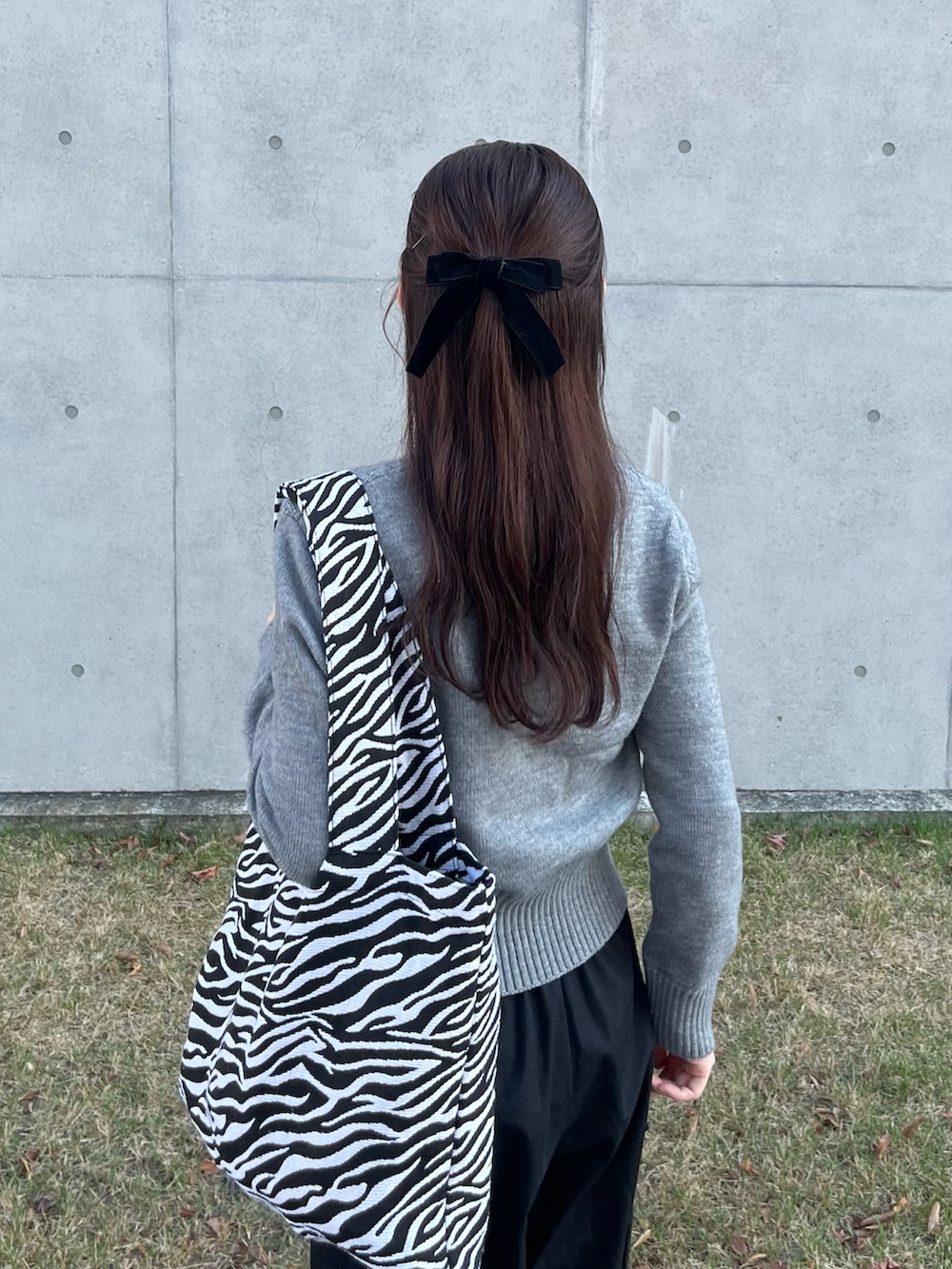 グレー系のニット/セーター、ブラック系のカーゴパンツ、ホワイト系のスニーカーを着用したレディースの秋コーディネートの2枚目の写真