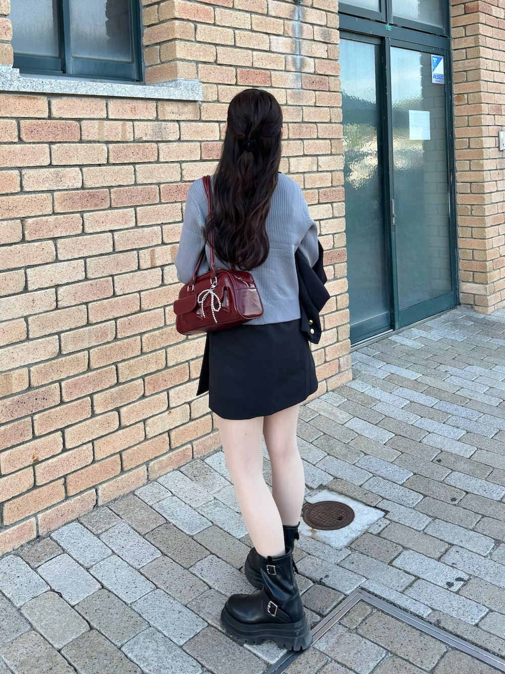 グレー系のカーディガン/ボレロ、レッド系のショルダーバッグ、ブラック系のスカートを着用したレディースの秋コーディネートの2枚目の写真