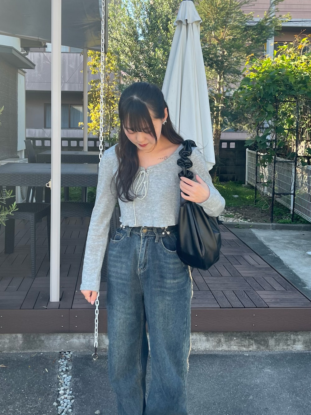 グレー系のニット/セーター、ブラック系のバッグ、ブルー系のデニムパンツを着用したレディースの春コーディネートの2枚目の写真