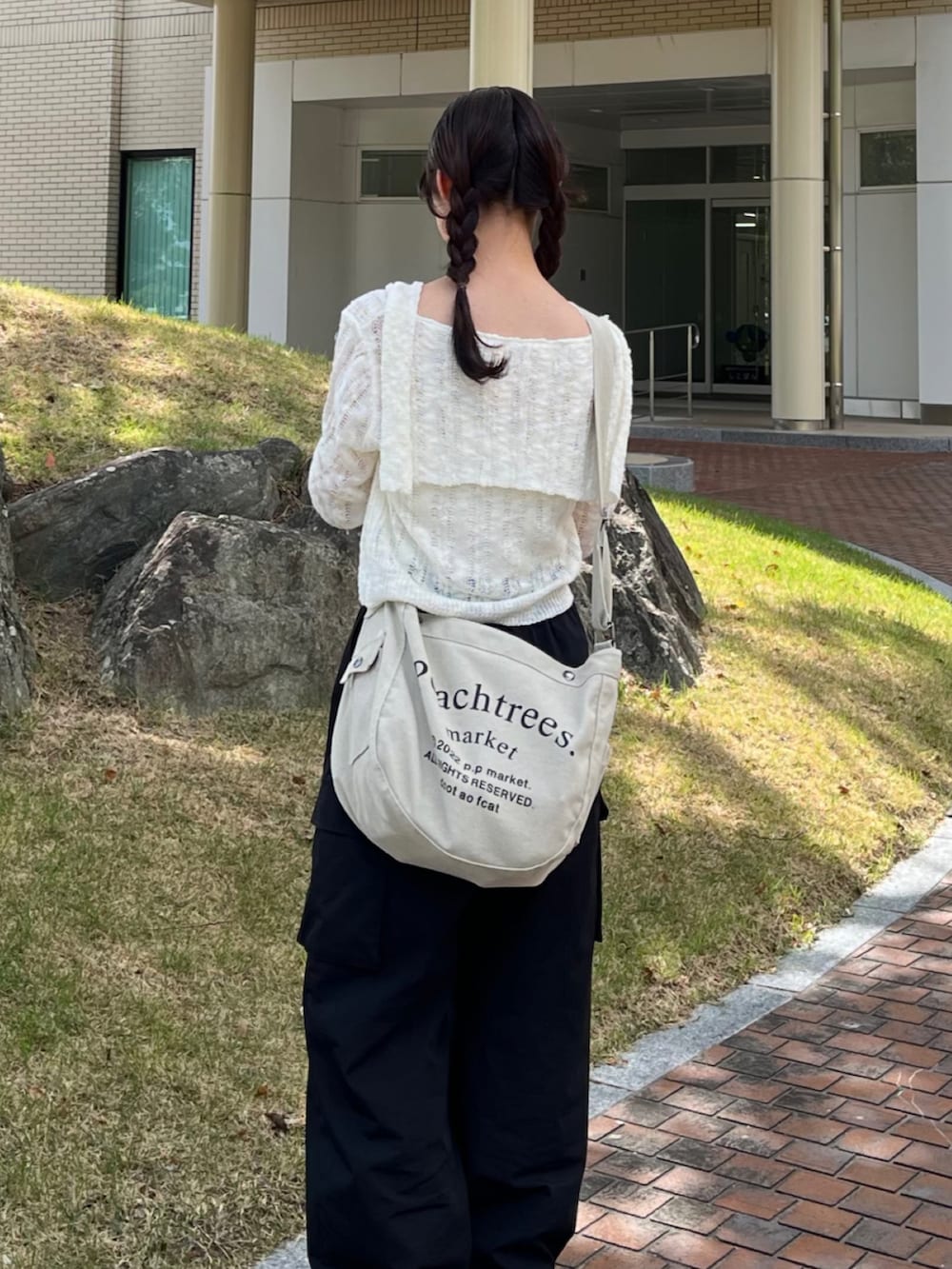 ベージュ系のショルダーバッグ、ブラック系のカーゴパンツ、ブラック系のスニーカーを着用したレディースの秋コーディネートの2枚目の写真