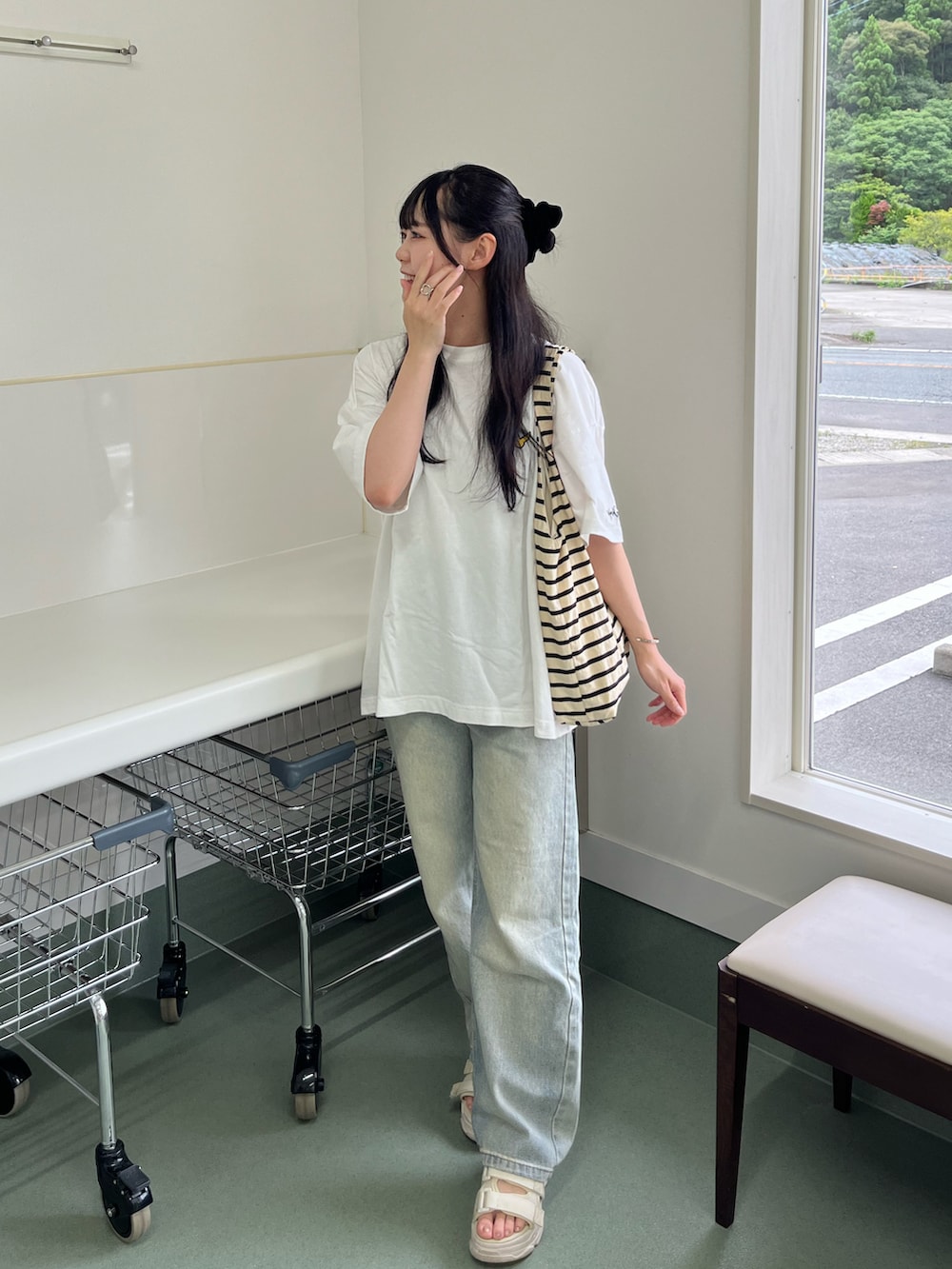ホワイト系のトートバッグ、ブルー系のデニムパンツ、ホワイト系のサンダルを着用したレディースの夏コーディネートの2枚目の写真