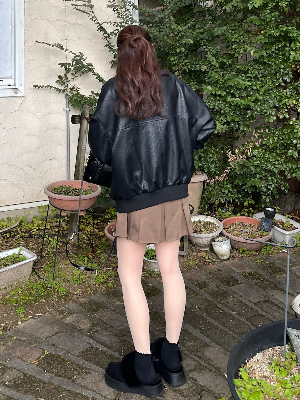 ブラック系のスリッポン、ブラウン系のスカート、ブラック系のブルゾンを着用したレディースの冬コーディネートの2枚目の写真