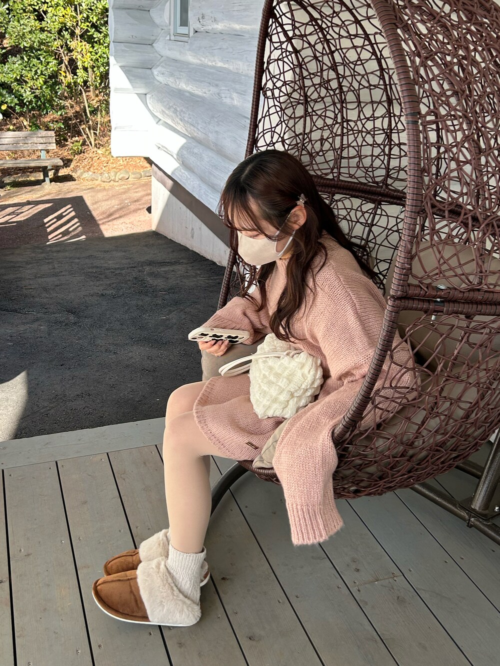 ピンク系のニット/セーター、ブラウン系のスリッポン、ホワイト系のショルダーバッグを着用したレディースの春コーディネートの2枚目の写真