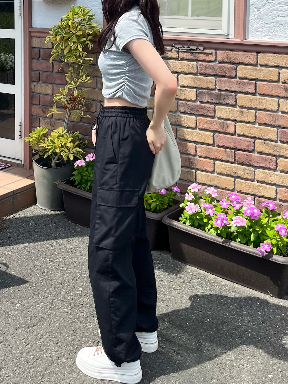 グレー系のTシャツ/カットソー、ベージュ系のショルダーバッグ、ブラック系のカーゴパンツを着用したレディースの夏コーディネートの2枚目の写真