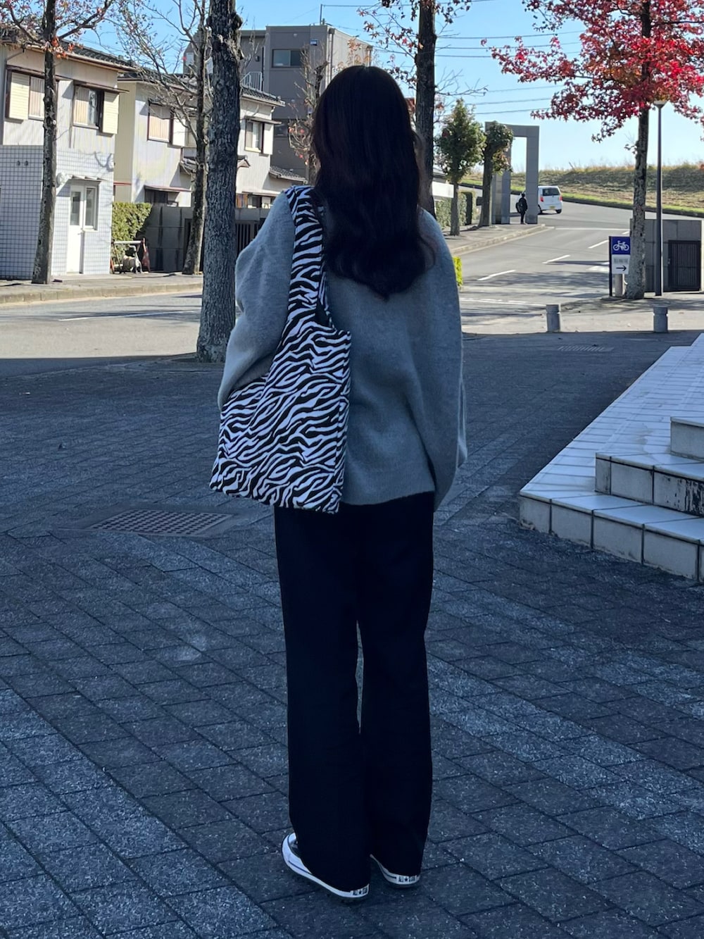 グレー系のニット/セーター、ホワイト系のトートバッグ、ブラック系のスラックスを着用したレディースの冬コーディネートの2枚目の写真