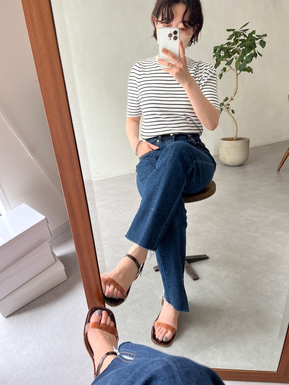 ブルー系のデニムパンツ、ブラウン系のサンダル、ブルー系のトートバッグを着用したレディースの春コーディネートの2枚目の写真