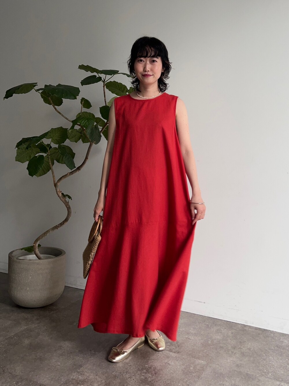 レッド系のワンピース、イエロー系のかごバッグ、ゴールド系のバレエシューズを着用したレディースの春コーディネートの2枚目の写真