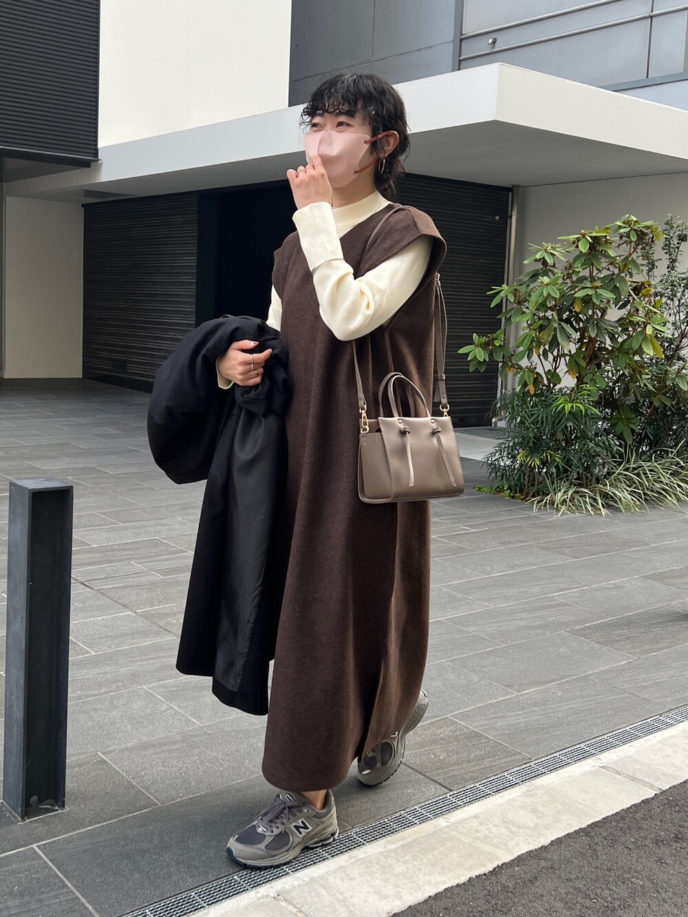 ブラウン系のワンピース、ブラウン系のショルダーバッグ、ブラック系のブルゾンを着用したレディースの秋コーディネートの2枚目の写真