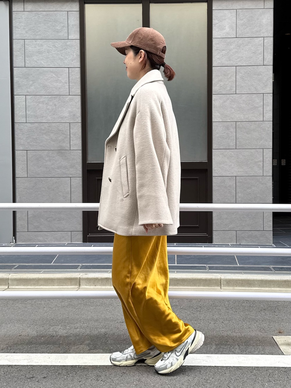 ベージュ系のピーコート、グレー系のニット/セーター、シルバー系のスニーカーを着用したレディースの秋コーディネートの2枚目の写真