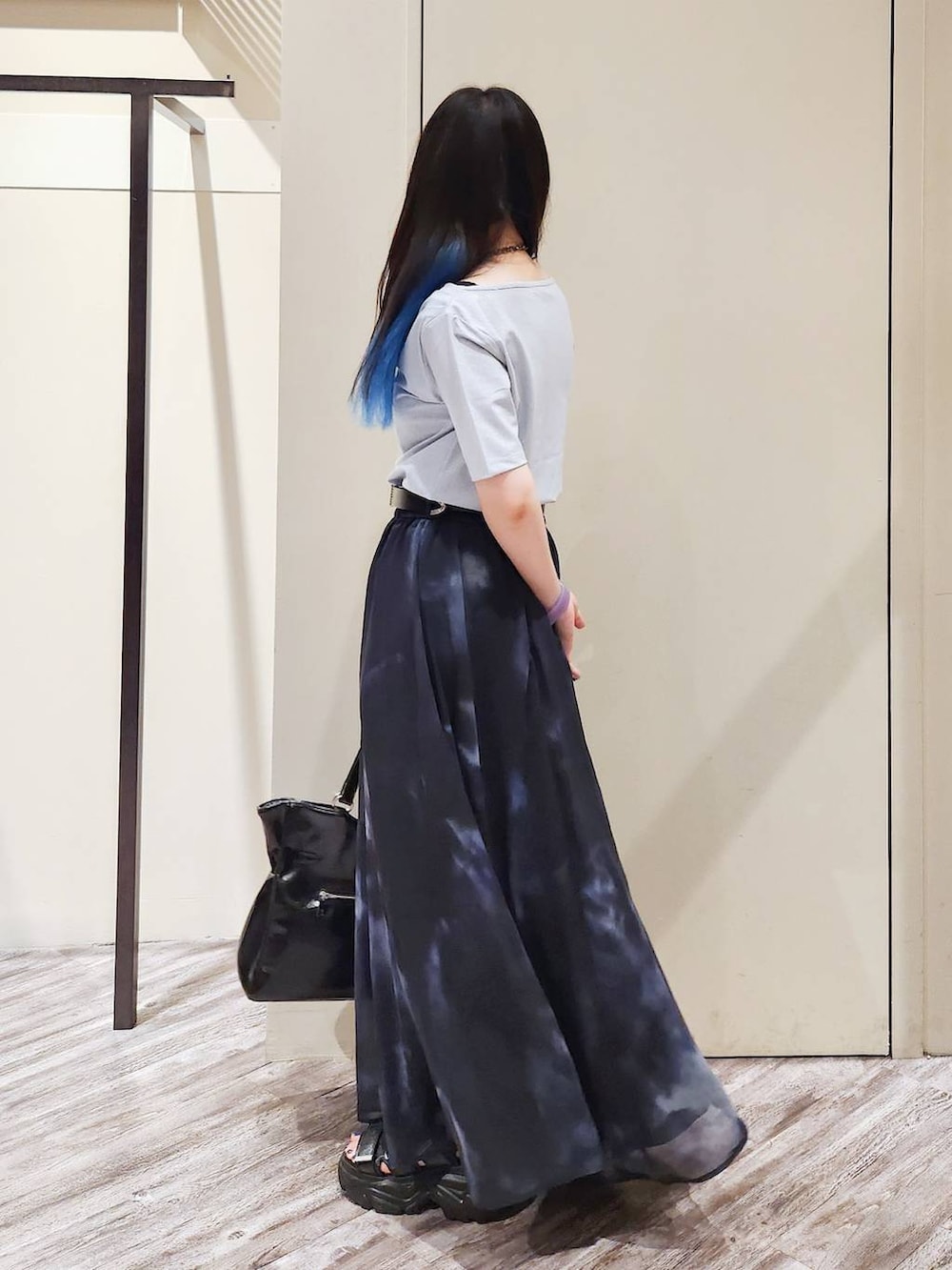 ブラック系のスカート、ブラック系のサンダル、グレー系のTシャツ/カットソーを着用したレディースの秋コーディネートの5枚目の写真