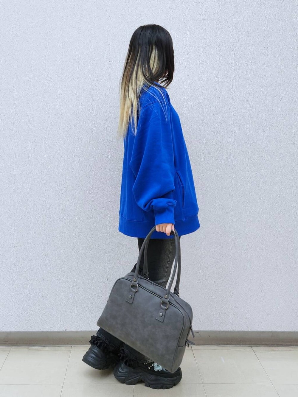 ブラック系のデニムパンツ、グレー系のボストンバッグ、ブルー系のTシャツ/カットソーを着用したレディースの秋コーディネートの3枚目の写真