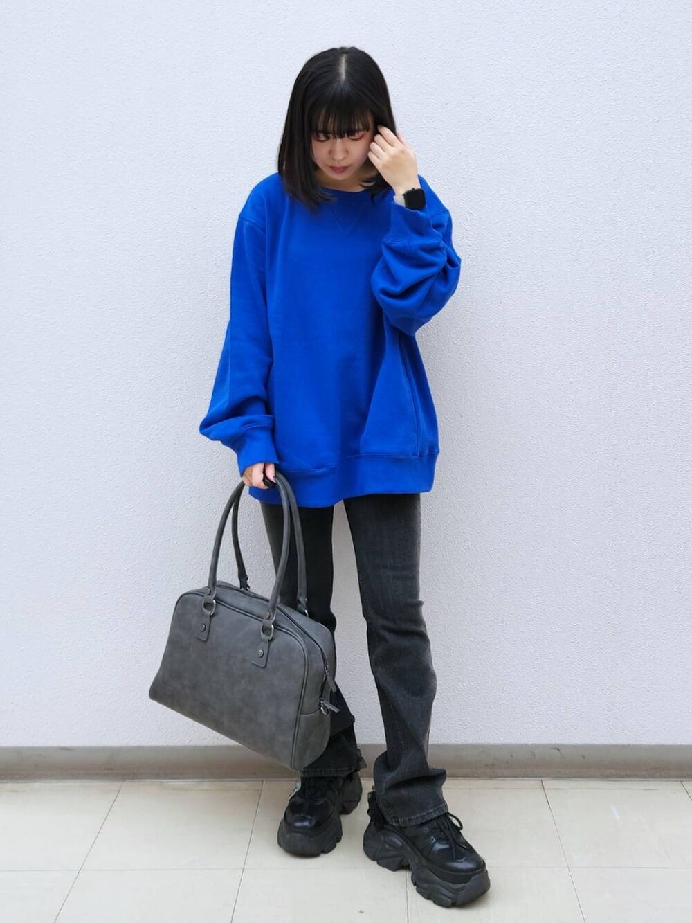 ブラック系のデニムパンツ、グレー系のボストンバッグ、ブルー系のTシャツ/カットソーを着用したレディースの秋コーディネートの2枚目の写真