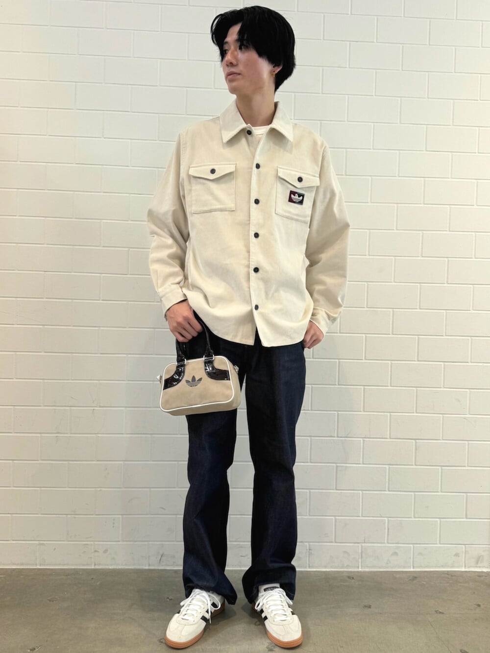 ベージュ系のスニーカー、ホワイト系のTシャツ/カットソー、ベージュ系のショルダーバッグを着用したメンズの秋コーディネートの3枚目の写真