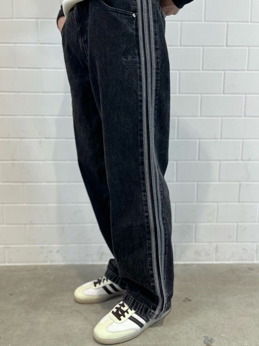 ブラック系のデニムパンツ、ホワイト系のニット/セーター、ホワイト系のスニーカーを着用したメンズの秋コーディネートの5枚目の写真