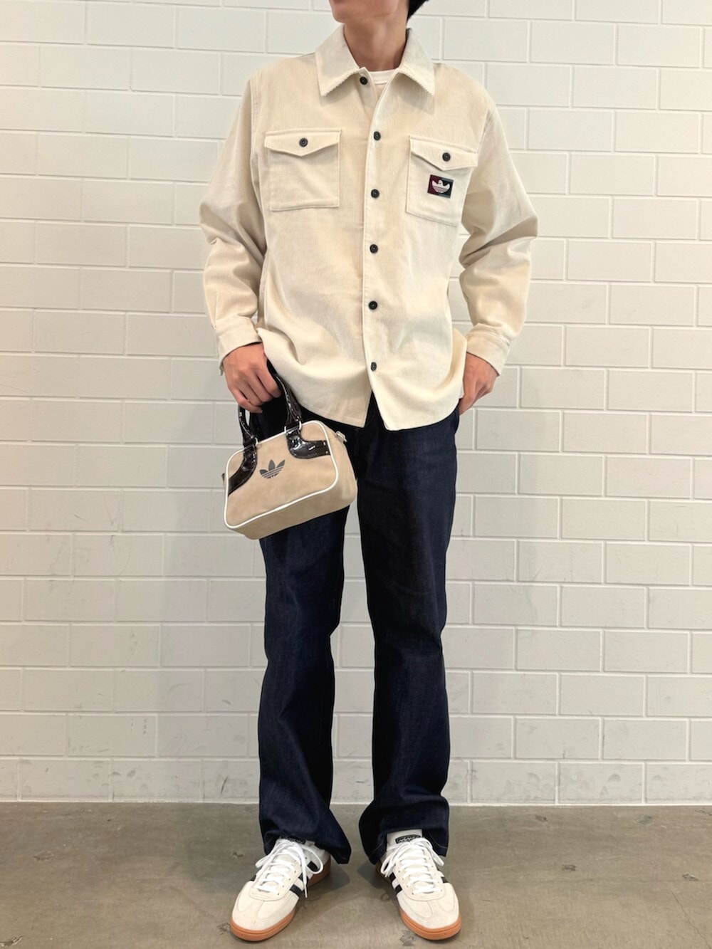 ベージュ系のスニーカー、ホワイト系のTシャツ/カットソー、ベージュ系のショルダーバッグを着用したメンズの秋コーディネートの2枚目の写真