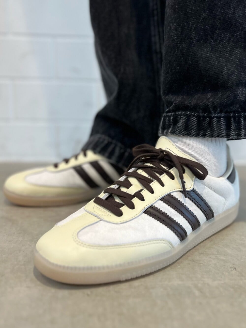 ブラック系のデニムパンツ、ホワイト系のニット/セーター、ホワイト系のスニーカーを着用したメンズの秋コーディネートの6枚目の写真