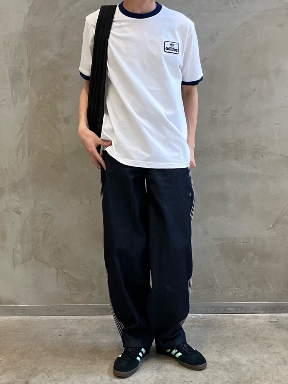 ブラック系のショルダーバッグ、ブルー系のデニムパンツ、ブラック系のスニーカーを着用したメンズの夏コーディネートの2枚目の写真