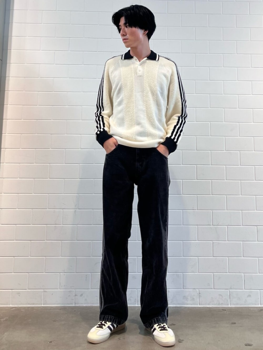 ブラック系のデニムパンツ、ホワイト系のニット/セーター、ホワイト系のスニーカーを着用したメンズの秋コーディネートの3枚目の写真