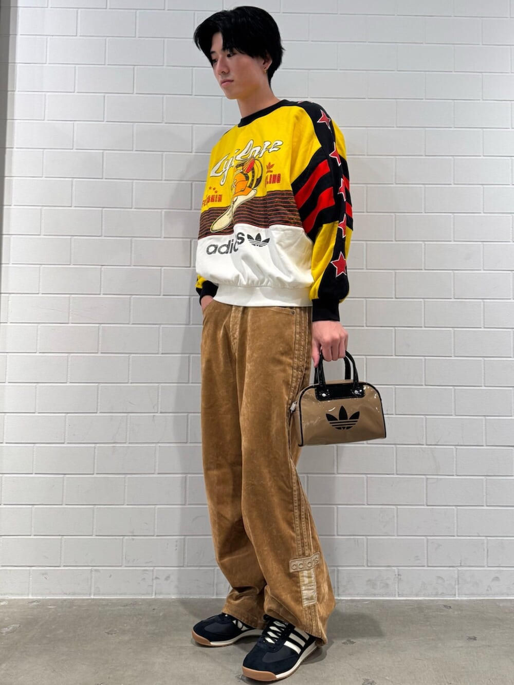 ベージュ系のショルダーバッグ、イエロー系のスウェット、ブラウン系のその他パンツを着用したメンズの秋コーディネートの3枚目の写真