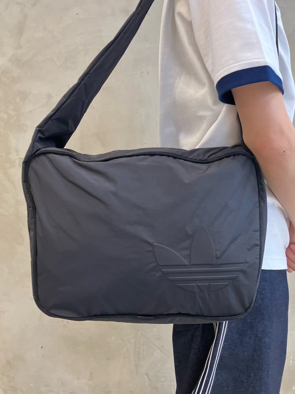 ブラック系のショルダーバッグ、ブルー系のデニムパンツ、ブラック系のスニーカーを着用したメンズの夏コーディネートの3枚目の写真