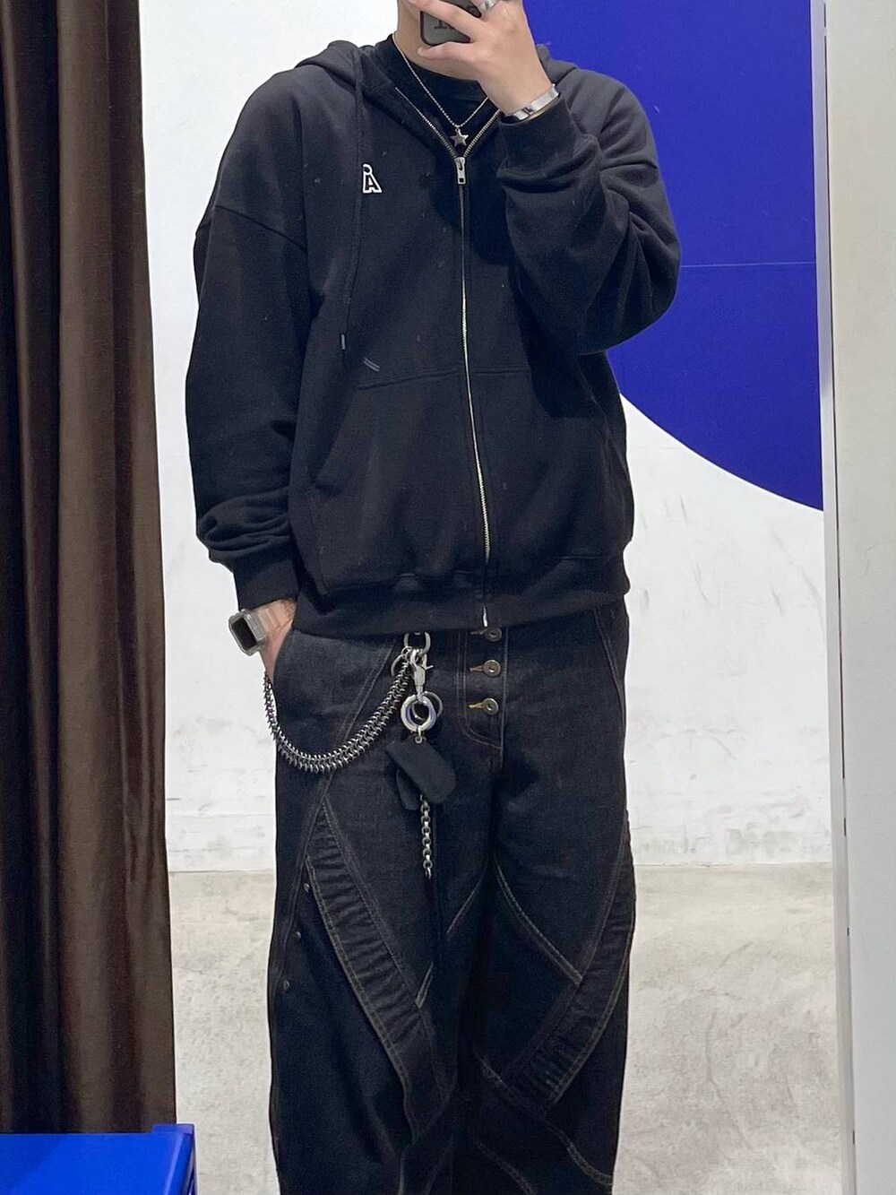 ブラック系のパーカー、ブラック系のデニムパンツ、ブラウン系のキャップを着用したメンズの秋コーディネートの2枚目の写真