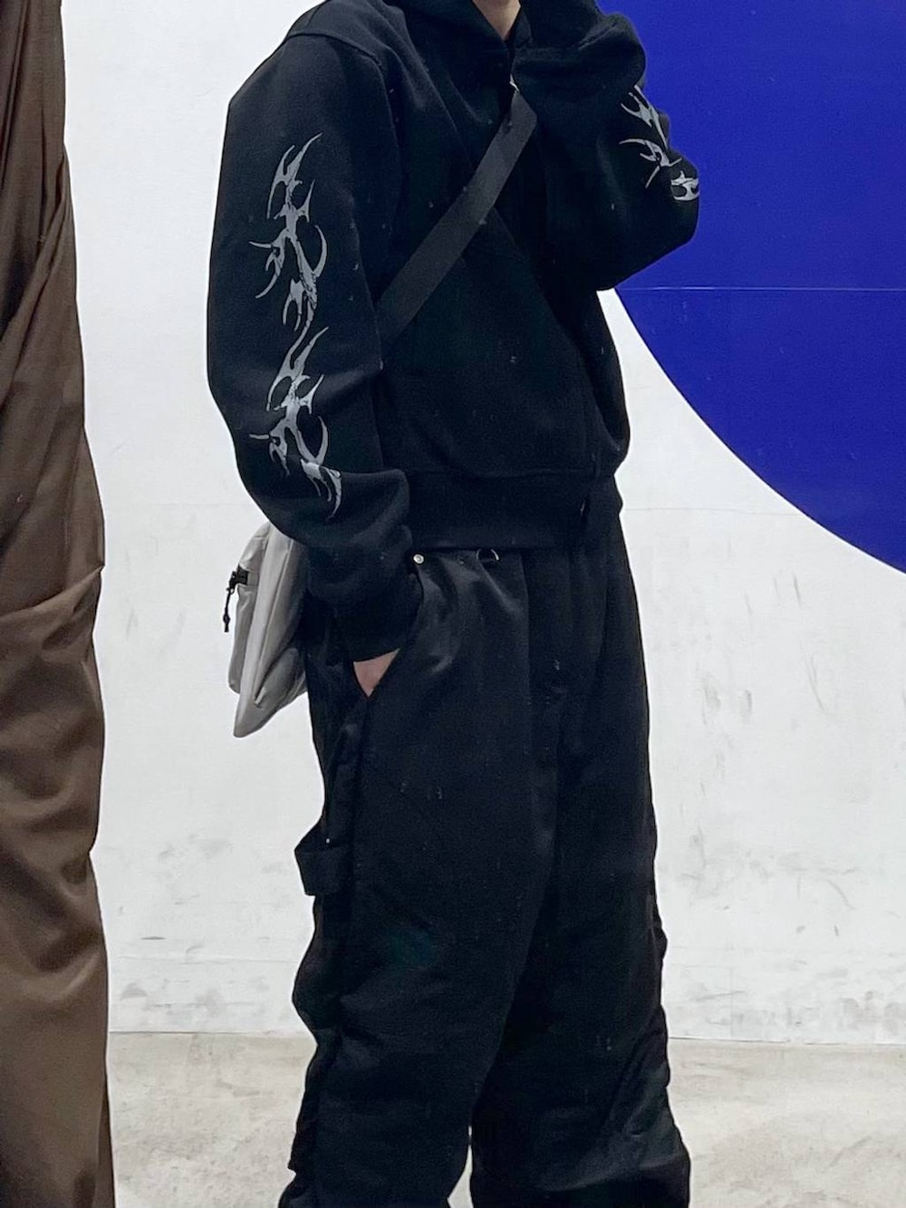 グレー系のショルダーバッグ、ブラック系のその他パンツ、ブラック系のパーカーを着用したメンズの春コーディネートの2枚目の写真