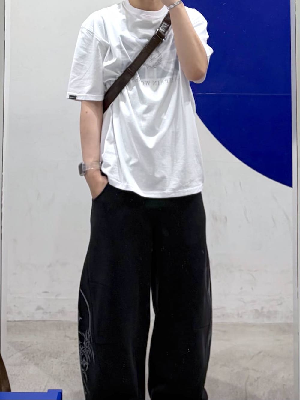 ホワイト系のTシャツ/カットソー、ブラック系のスウェットパンツ、ブラウン系のショルダーバッグを着用したメンズの春コーディネートの2枚目の写真