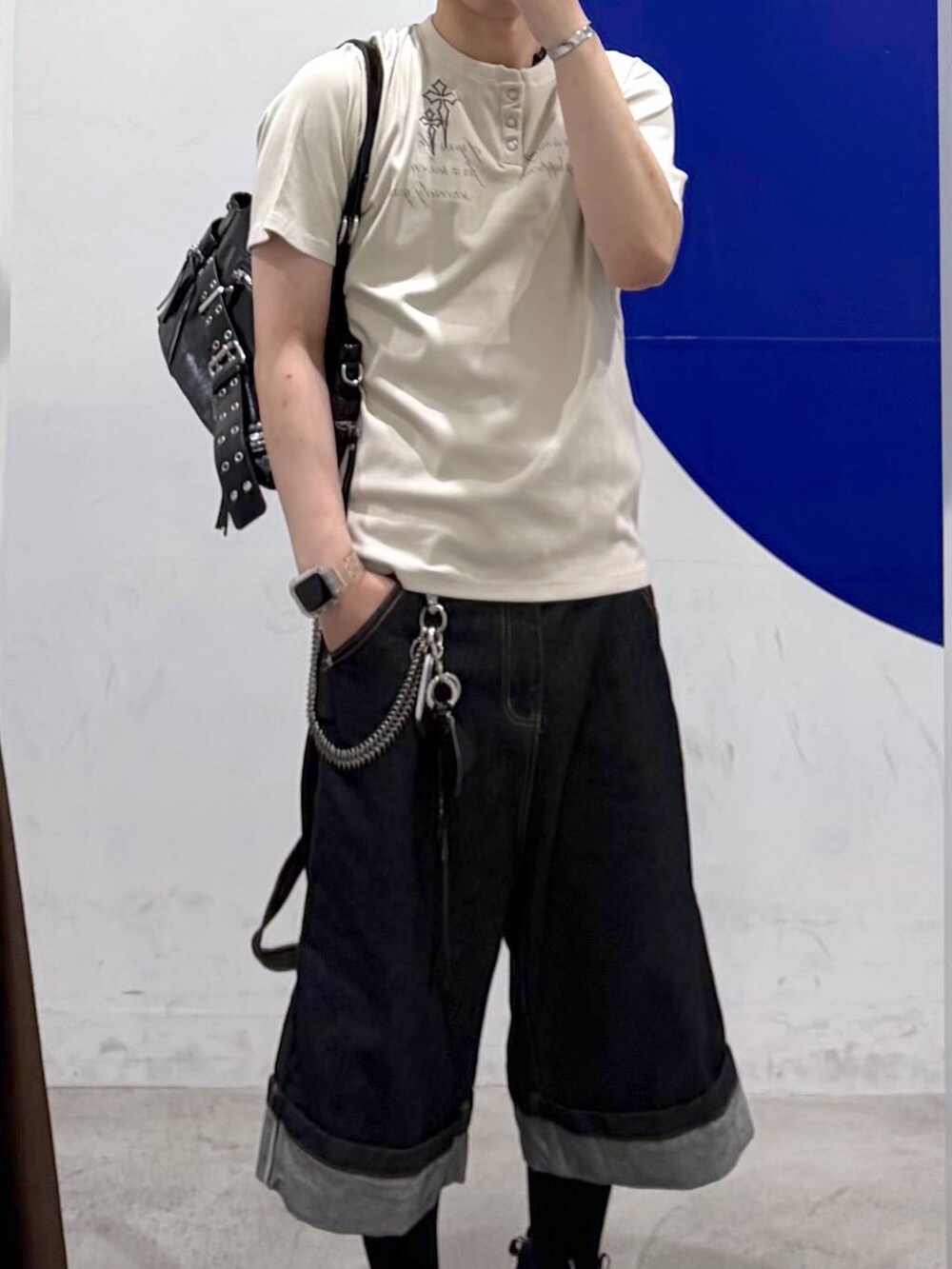 ブラック系のショルダーバッグ、ブルー系のデニムパンツ、ベージュ系のTシャツ/カットソーを着用したメンズの夏コーディネートの2枚目の写真