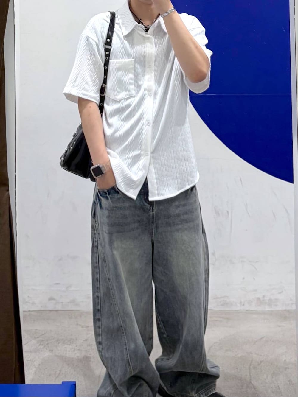 ブルー系のデニムパンツ、ブラック系のショルダーバッグ、ホワイト系のシャツ/ブラウスを着用したメンズの夏コーディネートの2枚目の写真