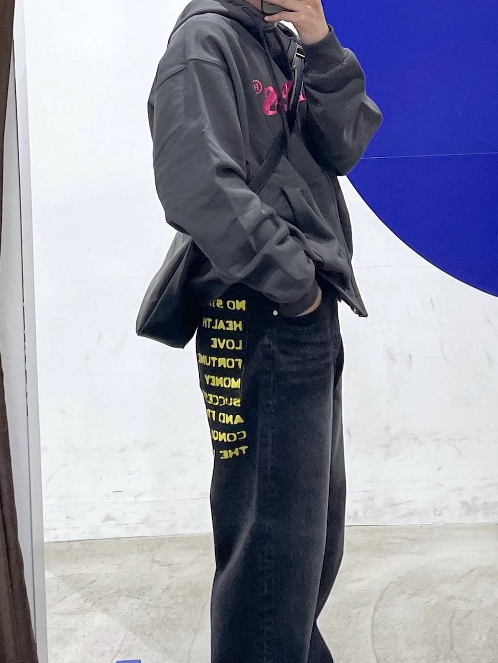 ブラック系のショルダーバッグ、グレー系のパーカー、ブラック系のデニムパンツを着用したメンズの冬コーディネートの3枚目の写真