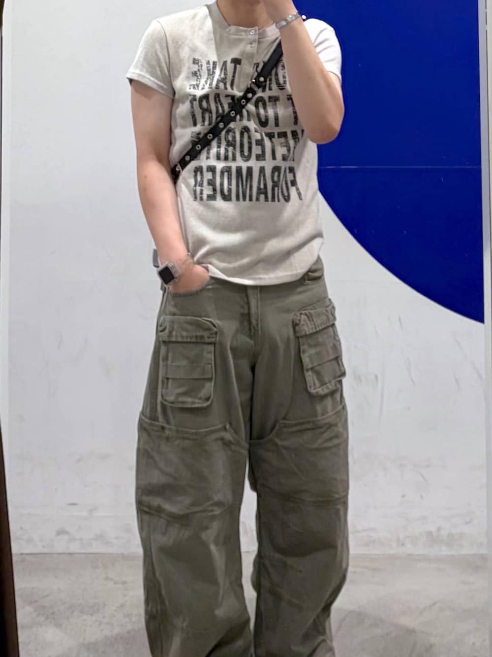 ベージュ系のTシャツ/カットソー、グリーン系のカーゴパンツ、ブラック系のショルダーバッグを着用したメンズの夏コーディネートの2枚目の写真