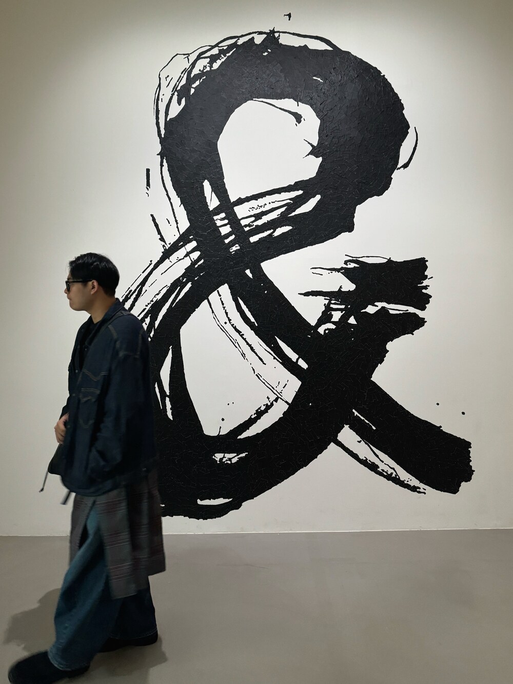 ブルー系のデニムジャケット、ブラック系のメッセンジャーバッグ、グリーン系のスカートを着用したメンズの秋コーディネートの4枚目の写真