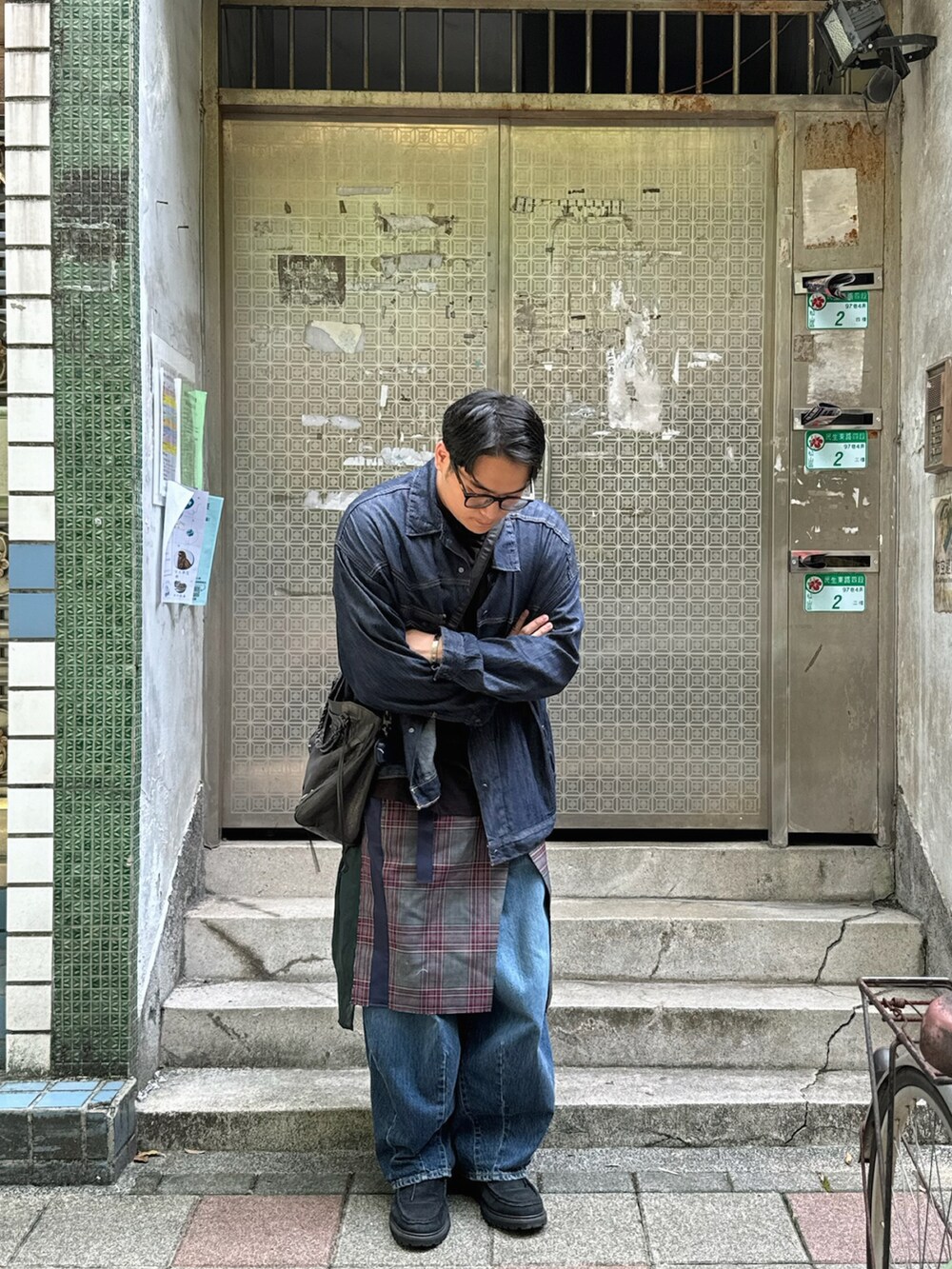 ブルー系のデニムジャケット、ブラック系のメッセンジャーバッグ、グリーン系のスカートを着用したメンズの秋コーディネートの3枚目の写真