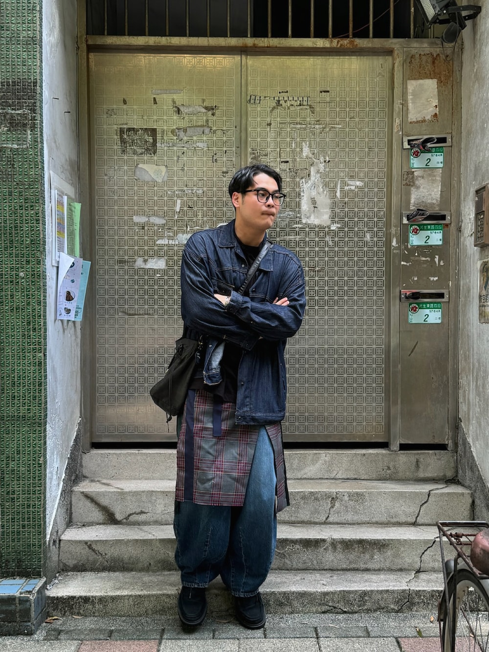 ブルー系のデニムジャケット、ブラック系のメッセンジャーバッグ、グリーン系のスカートを着用したメンズの秋コーディネートの2枚目の写真