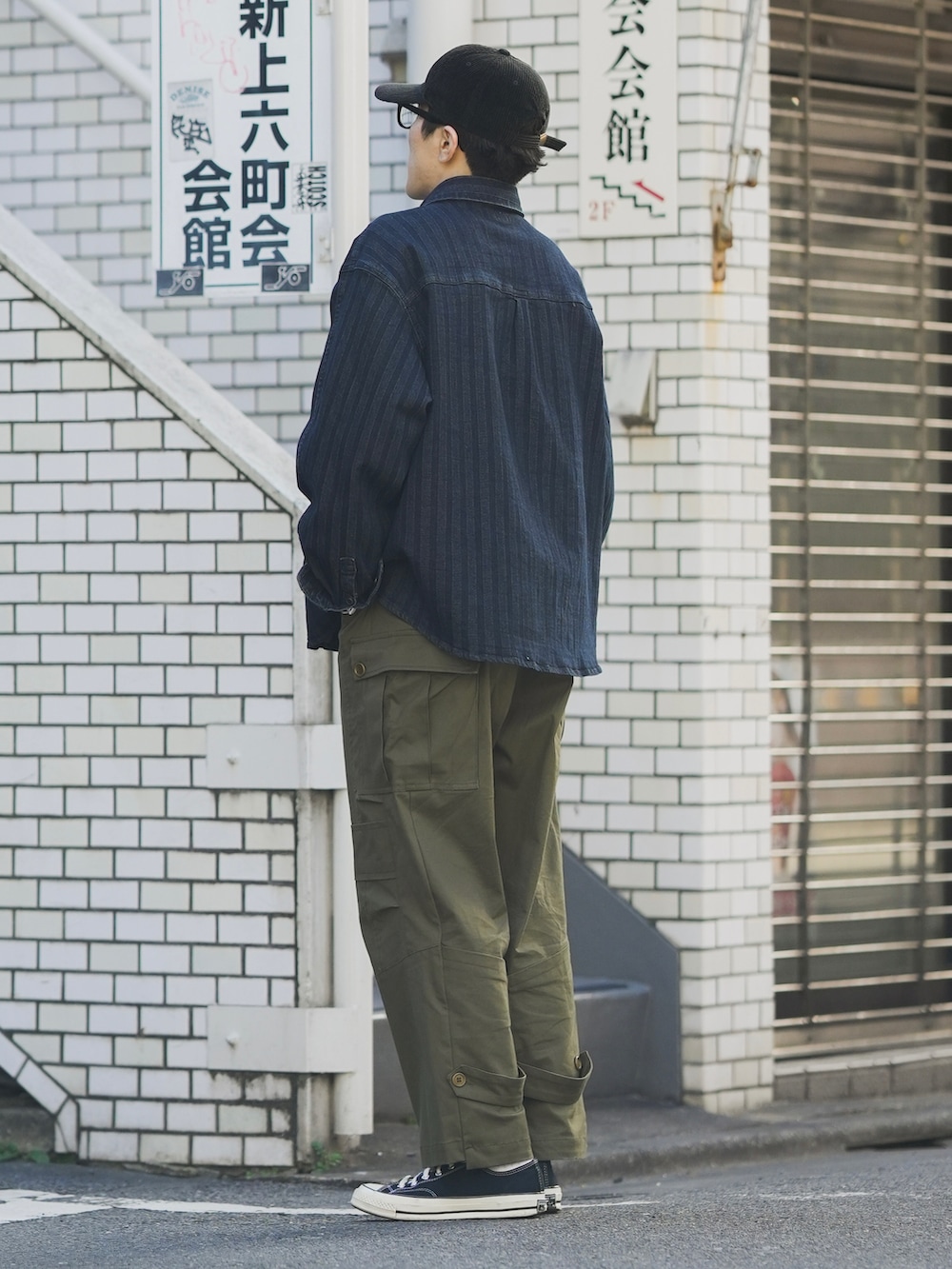 グリーン系のカーゴパンツ、ブルー系のデニムジャケット、ブラック系のスニーカーを着用したメンズの秋コーディネートの2枚目の写真