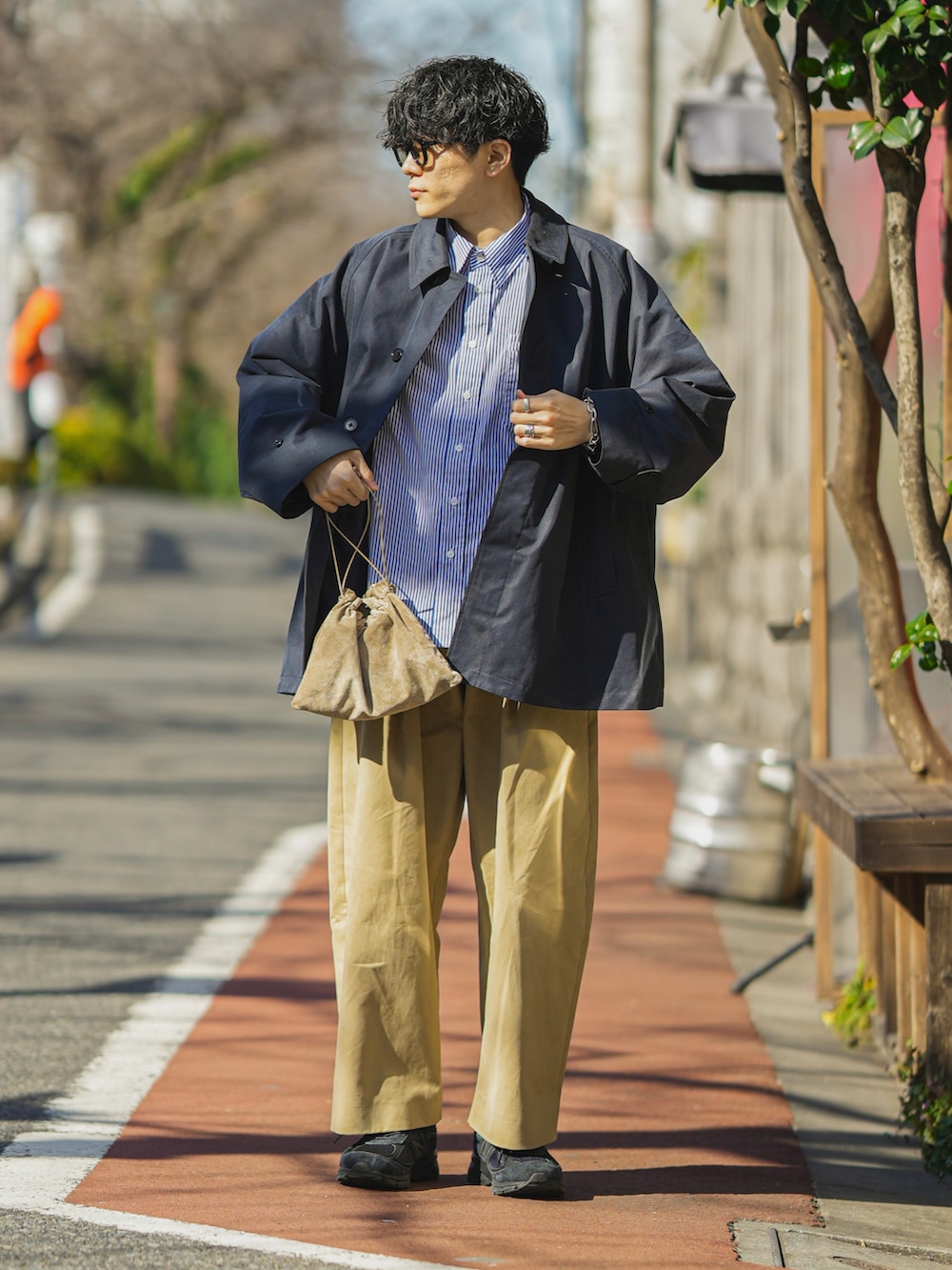 ブルー系のステンカラーコート、ベージュ系のショルダーバッグ、ベージュ系のチノパンツを着用したメンズの冬コーディネートの2枚目の写真