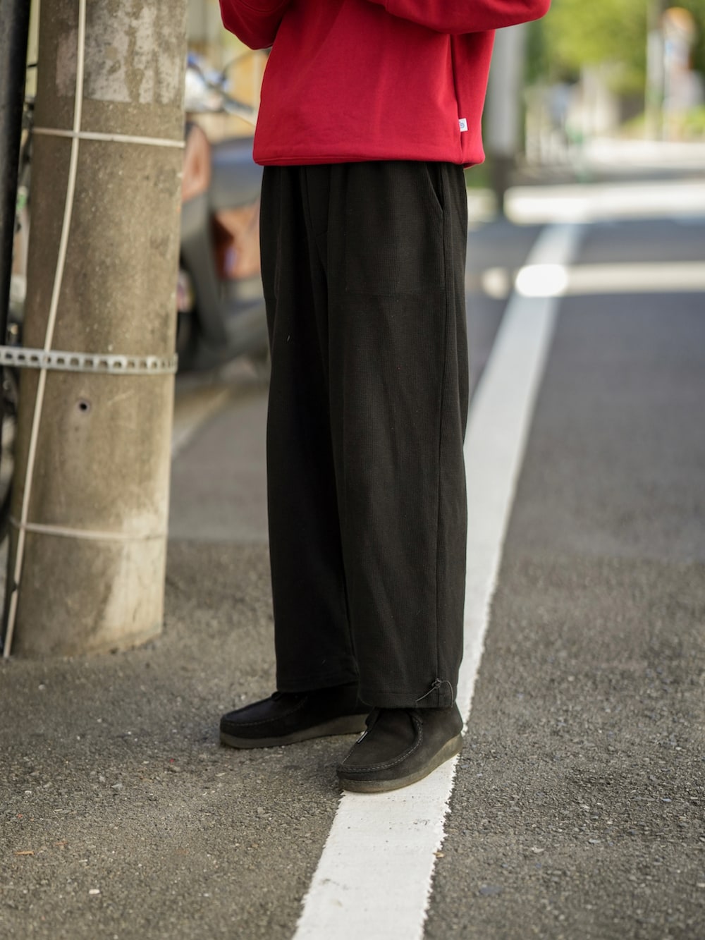 レッド系のスウェット、ブラック系のパンツ、ブラック系のモカシン/デッキシューズを着用したメンズの秋コーディネートの5枚目の写真