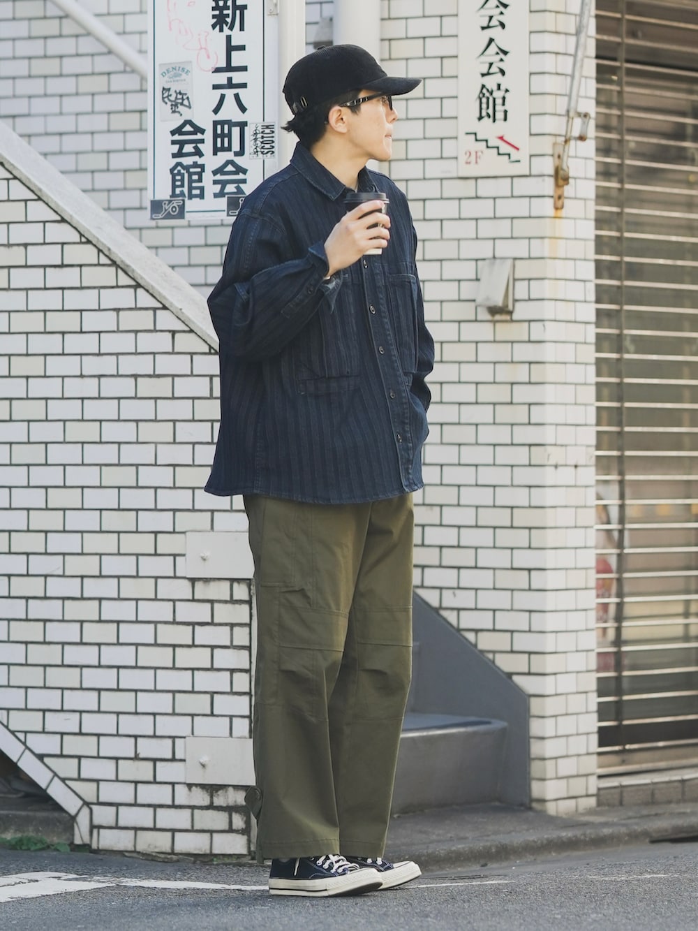 グリーン系のカーゴパンツ、ブルー系のデニムジャケット、ブラック系のスニーカーを着用したメンズの秋コーディネートの3枚目の写真