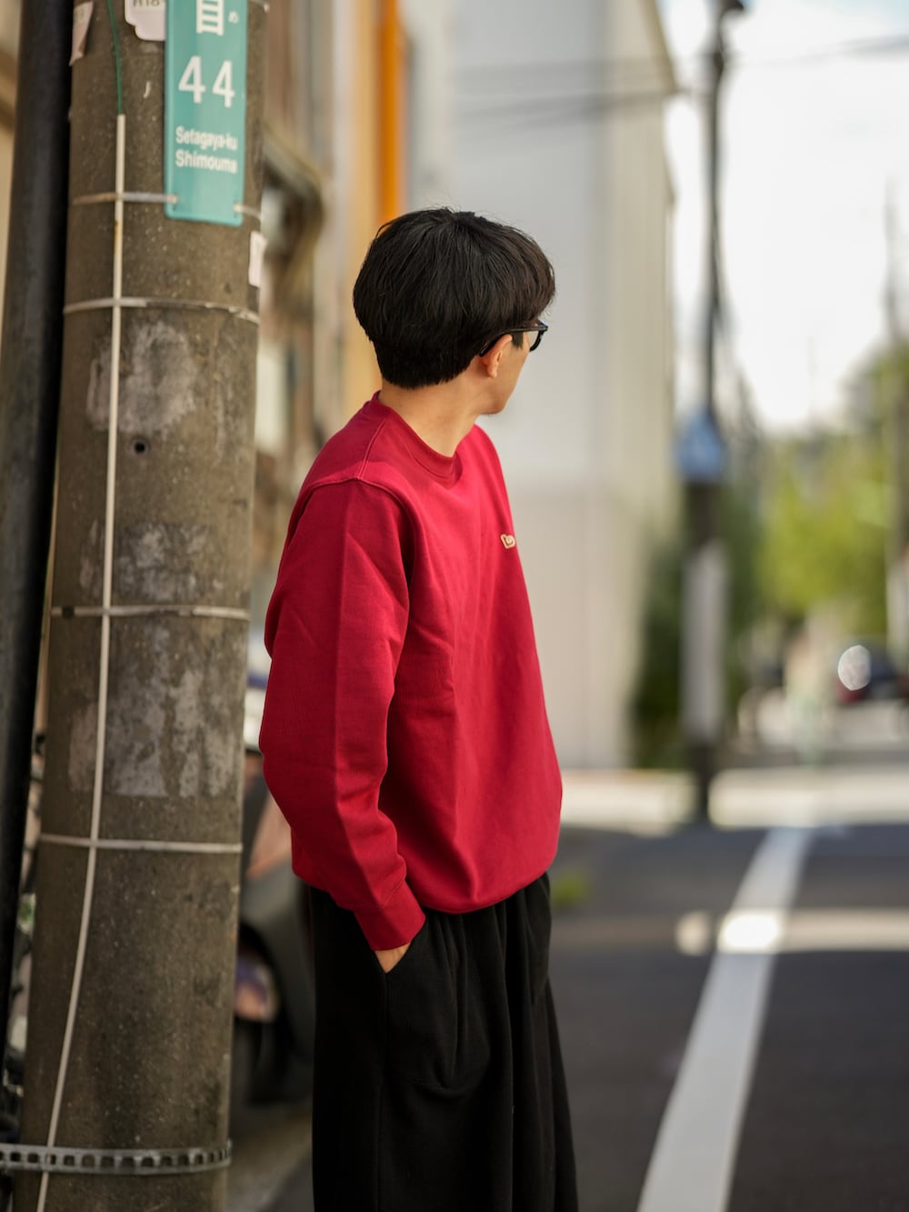 レッド系のスウェット、ブラック系のパンツ、ブラック系のモカシン/デッキシューズを着用したメンズの秋コーディネートの4枚目の写真