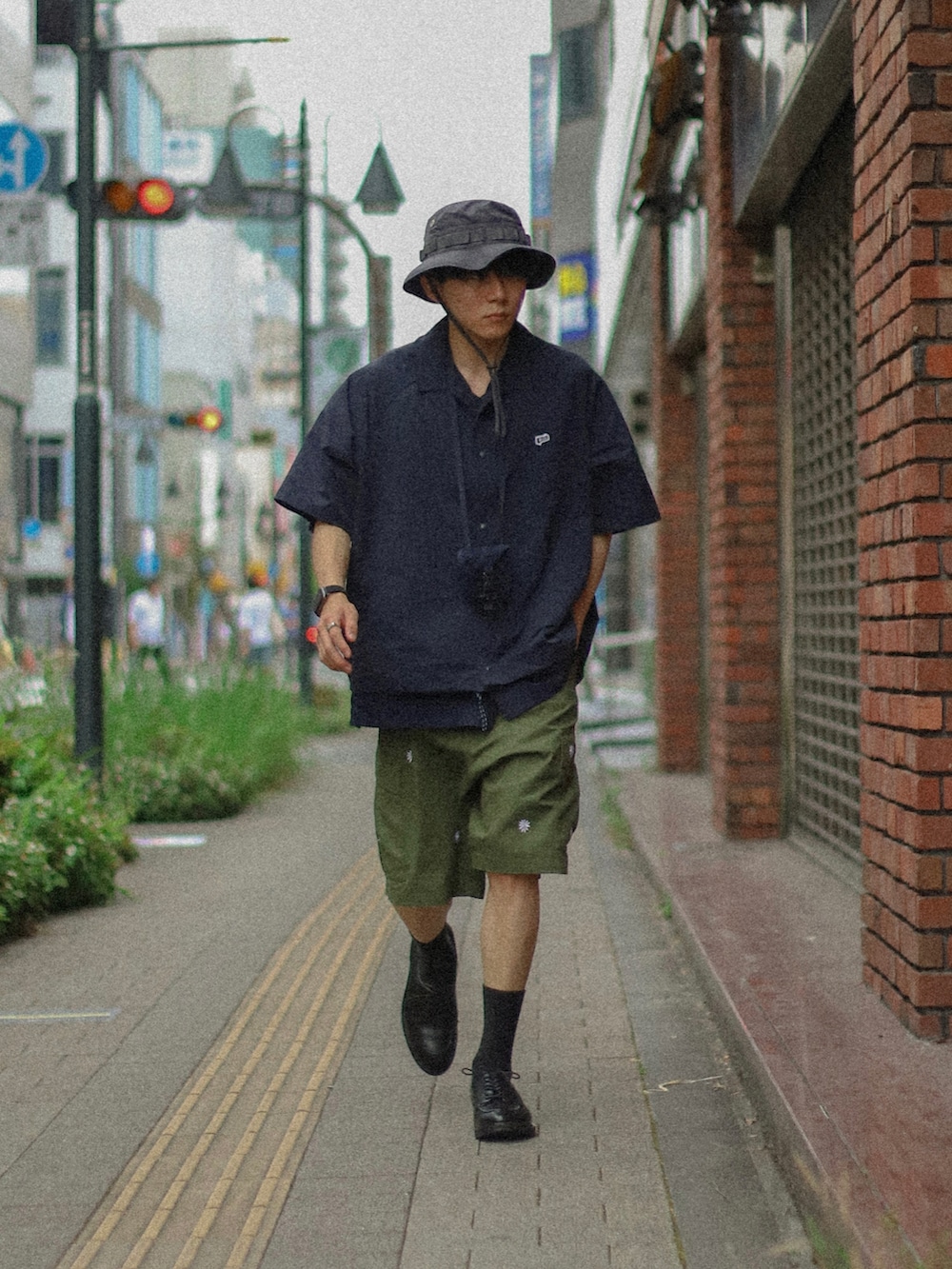 グリーン系のカーゴパンツ、ブラック系のドレスシューズ、ブルー系のハットを着用したメンズの夏コーディネートの2枚目の写真